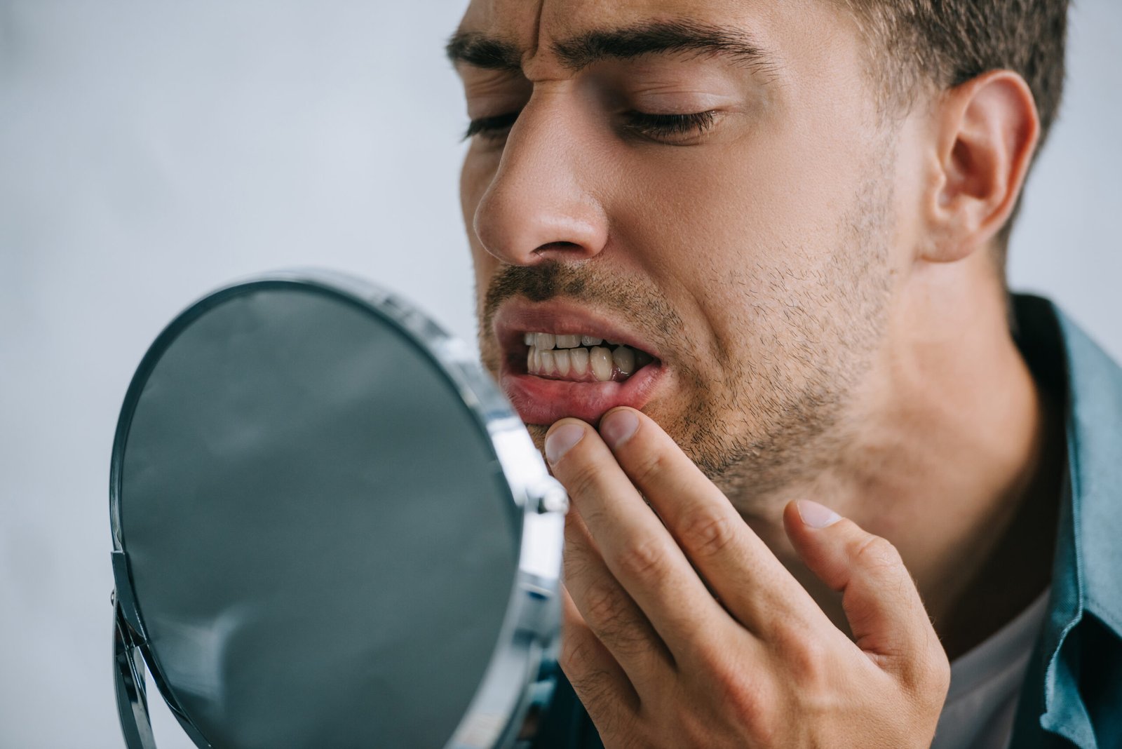 close-up view of young man with tooth pain looking at mirror