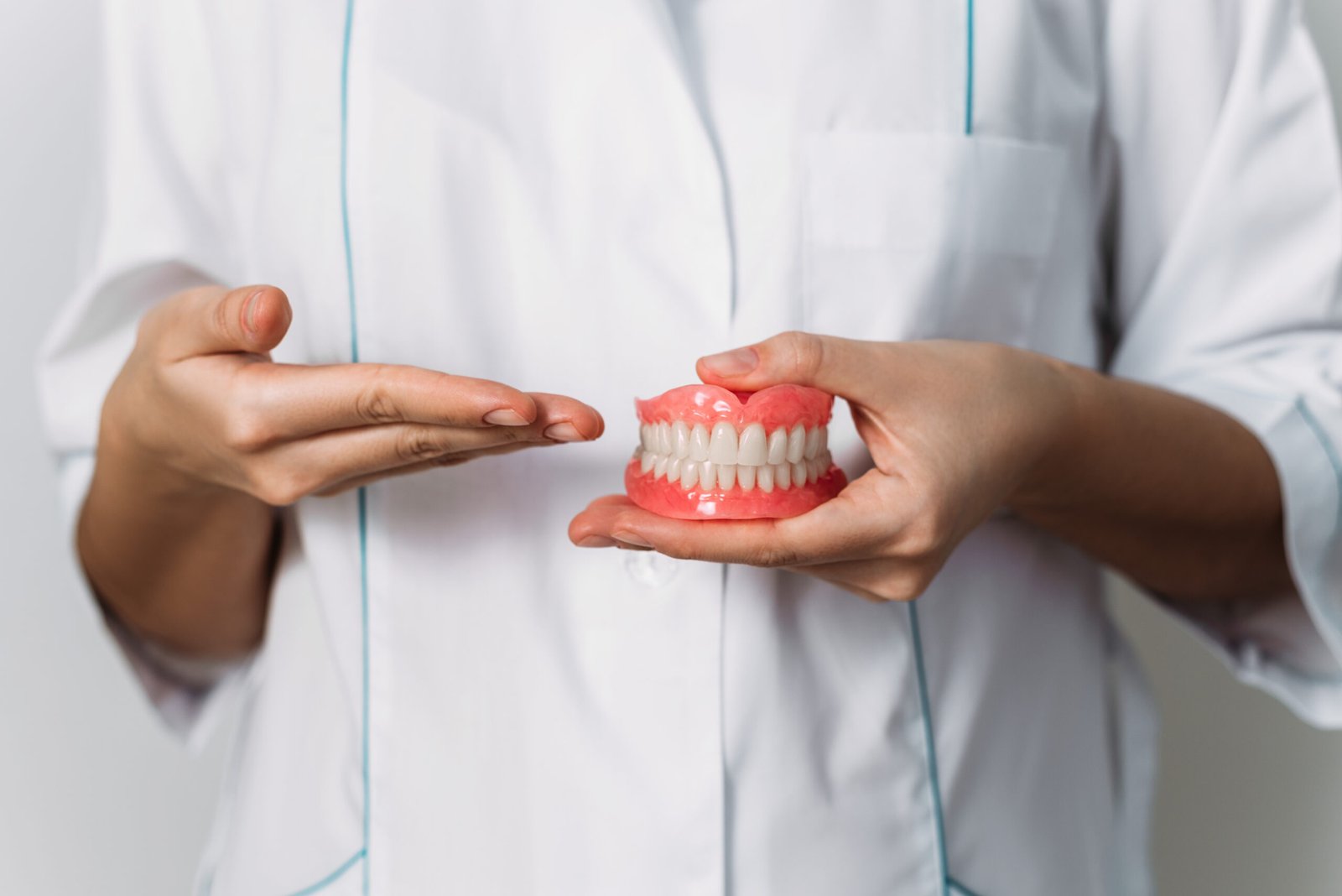 The dentist is holding dentures in his hands. Dental prosthesis in the hands of the doctor close-up. Front view of complete denture. Dentistry conceptual photo. Prosthetic dentistry. False teeth